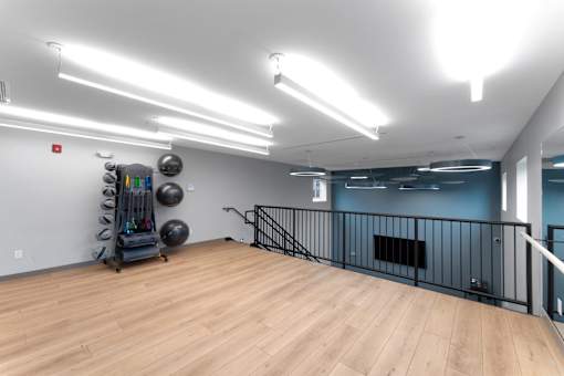 A gym with a wooden floor, a railing, and exercise equipment.