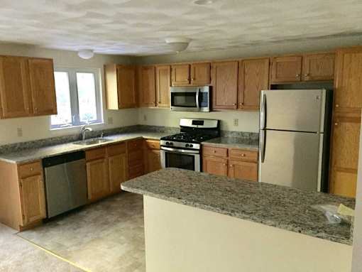 Birchwood Hills Townhomes Kitchen with oak cabinets, light colored floor, granite countertops and stainless steel appliances.