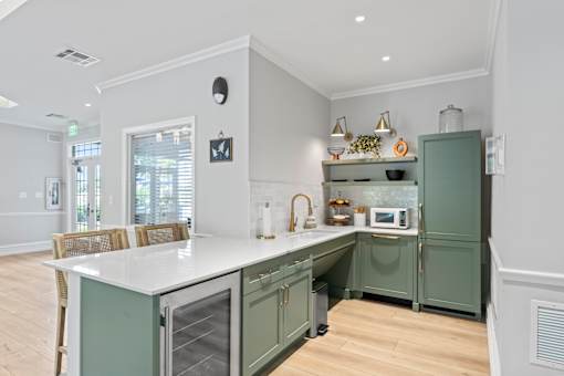 A kitchen with green cabinets and a white island.