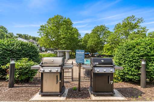 Two grills are in a fenced area with a sign in the background.