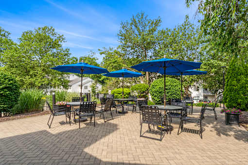 A patio with tables and chairs under blue umbrellas.