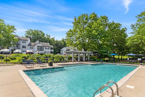 A swimming pool surrounded by trees and a building in the background.