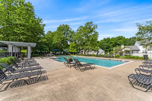 A pool area with lounge chairs and a clear blue sky.