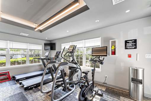 A gym with treadmills, exercise bikes and a TV.
