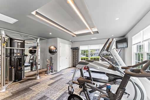 A gym with a row of treadmilers and a row of exercise bikes.
