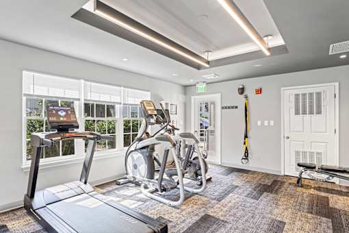 A gym with treadmills, exercise bikes, and a bench.