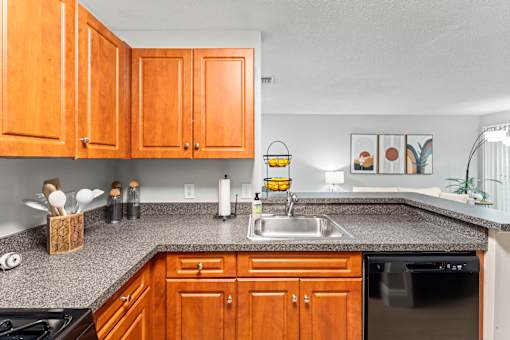 A kitchen with wooden cabinets and a black dishwasher.