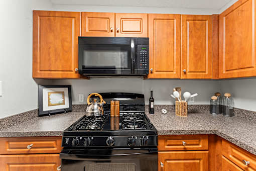 A kitchen with a black stove and wooden cabinets.