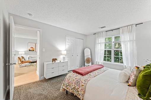 A bedroom with a bed, dresser, and chair.