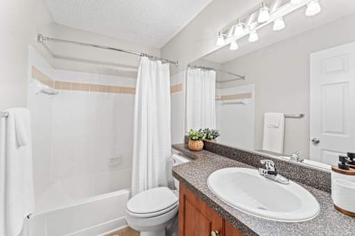 A white bathroom with a toilet, sink, and shower.
