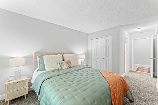 A bedroom with a large bed and a nightstand with a lamp.