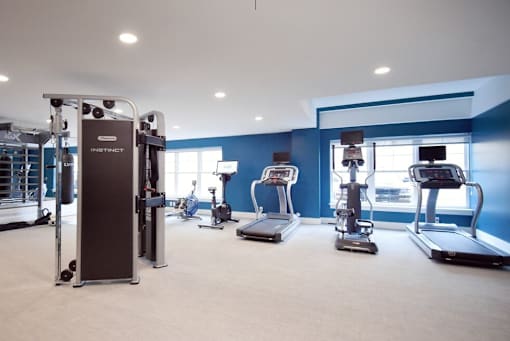 A gym with a variety of equipment including treadmills, weights, and exercise machines.
