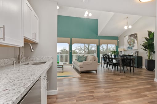 A kitchen with a granite countertop and a dining area with a table and chairs. at South Winds Apartments, Fall River