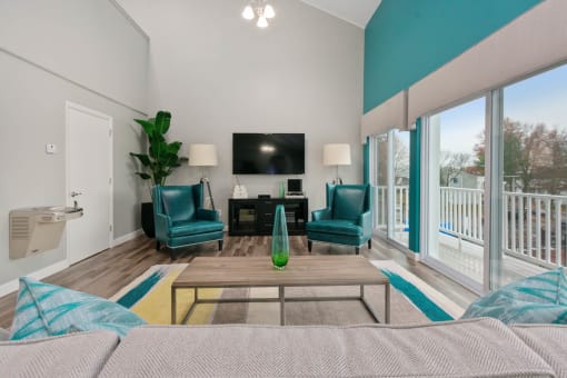 A living room with a television, two chairs, and a table. at South Winds Apartments, Fall River