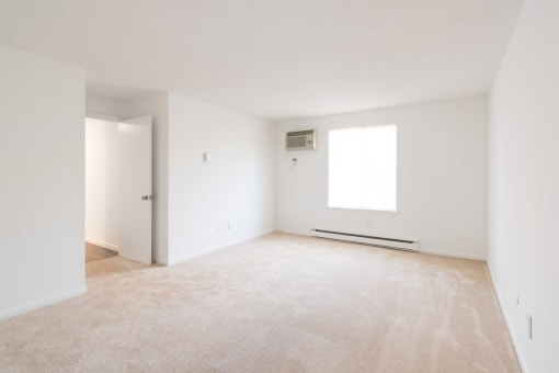 A room with a carpeted floor and a window. at South Winds Apartments, Fall River, Massachusetts