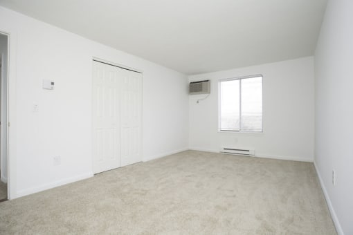 A white room with a carpeted floor and a window. at South Winds Apartments, Fall River