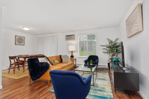 A living room with a blue chair and a wooden table. at South Winds Apartments, Fall River