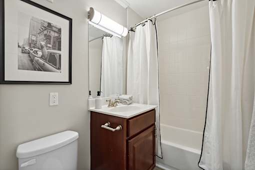 A bathroom with a white tub, sink, and shower curtain.