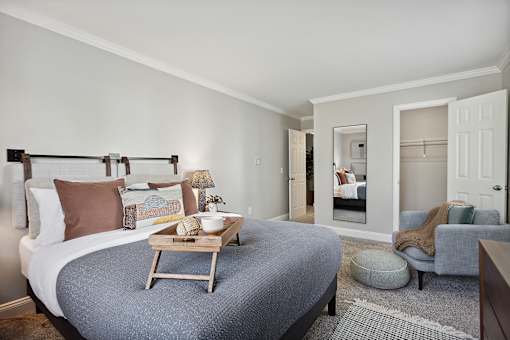 A bedroom with a bed, a chair, and a mirror.