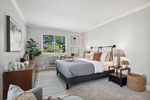 A bedroom with a large bed and a window overlooking a backyard.