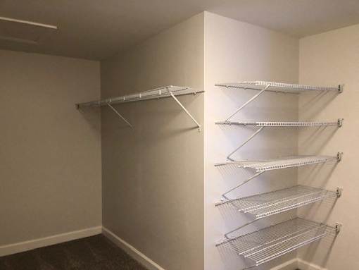 a walk in closet with empty shelves on the wall