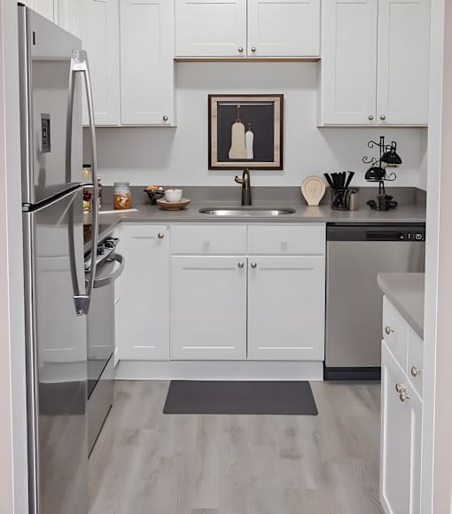 A modern kitchen with white cabinets and a stainless steel refrigerator.
