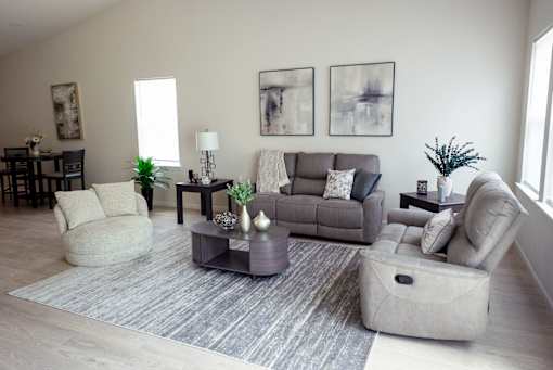 A living room with a grey couch, a grey armchair, a grey coffee table, and a grey rug.