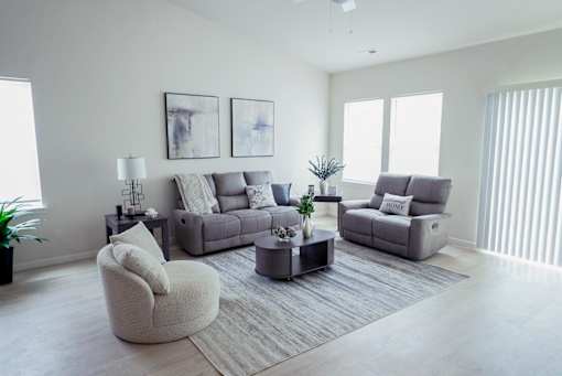 A living room with a grey sofa, a grey armchair, and a grey coffee table.