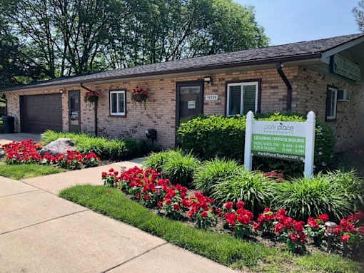 a building with a sign and flowers in front of it