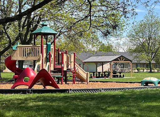 A playground with a red slide and a green roofed structure.