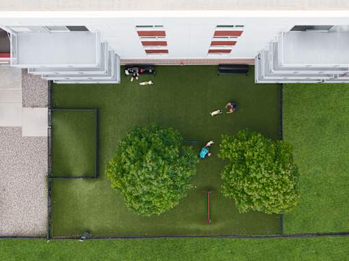 A man and a woman are playing badminton in a green yard.
