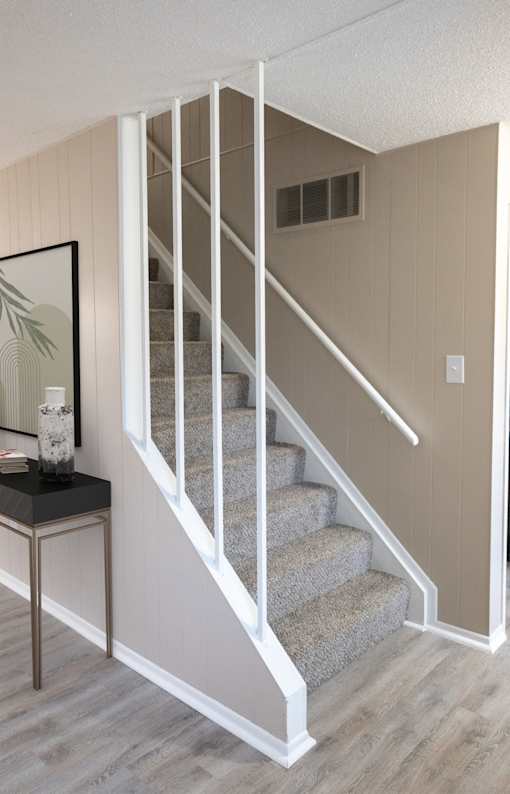 a set of stairs with white railings and gray carpet