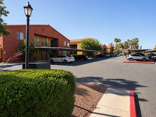 A street view of a building with a red hedge in the foreground.