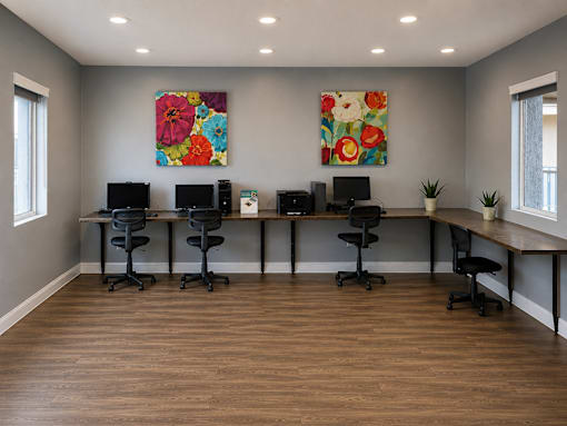 A room with a long table and chairs and two paintings on the wall.