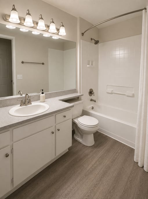A white bathroom with a toilet, sink, and shower.