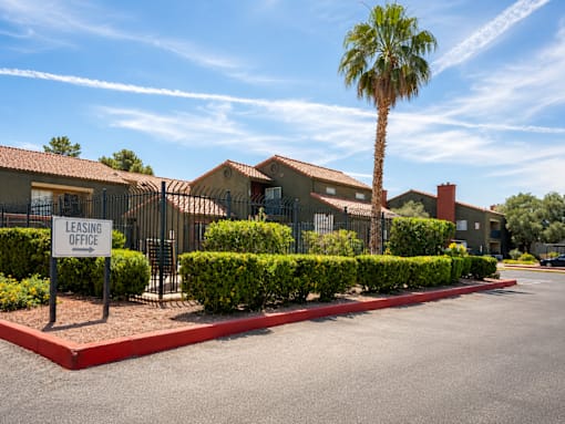 A leasing office sign is in front of a building with a palm tree.