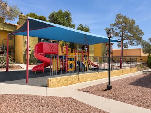 A playground with a red slide and a blue canopy.