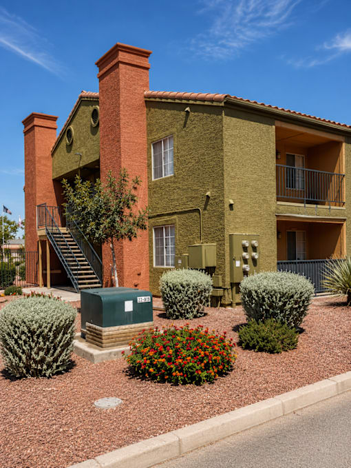 A red brick house with a green box in front.