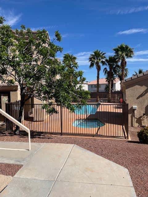 A pool surrounded by a fence and trees.