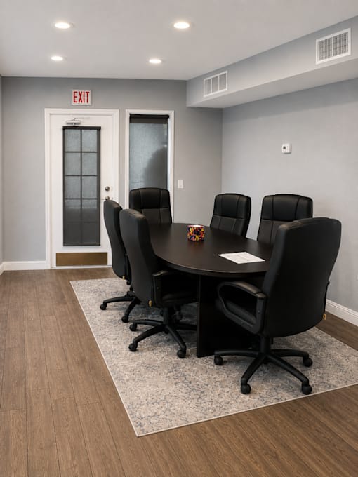 A conference room with a table, chairs, and an exit sign.