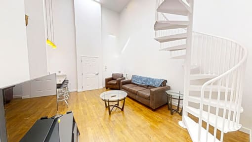 a living room with a spiral staircase in the background and a couch in the foreground