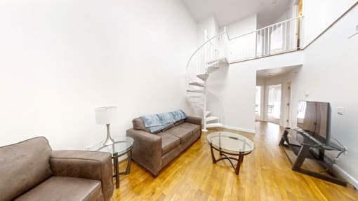a living room with a staircase in the background and a couch in the foreground