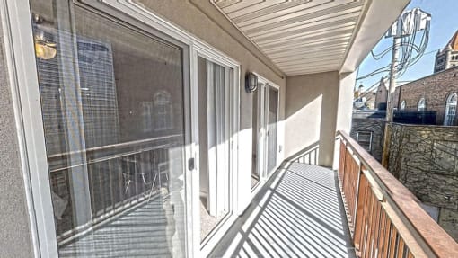 a balcony with a wooden railing and a glass door