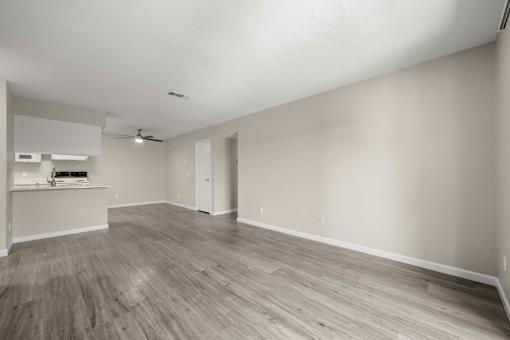 an empty living room and kitchen with wood flooring