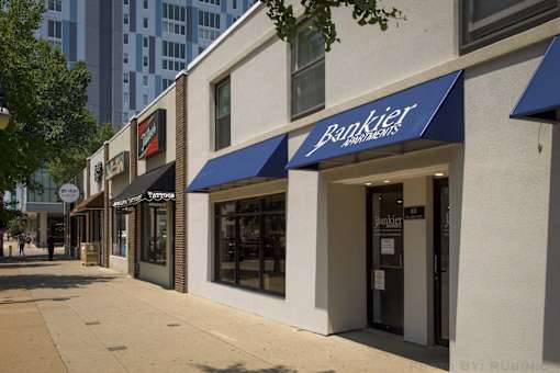 A banker's storefront with a blue awning on a sunny day.