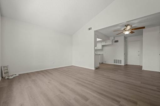 the living room and dining room of an empty house with a ceiling fan