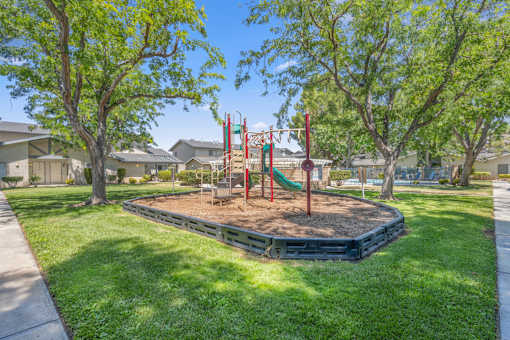 a playground in a park with trees and houses in the background