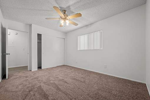the spacious living room with carpet and a ceiling fan