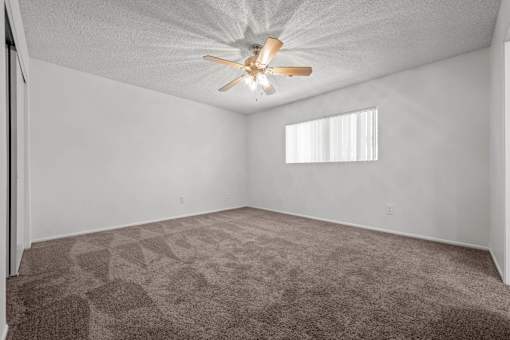 an empty living room with a ceiling fan