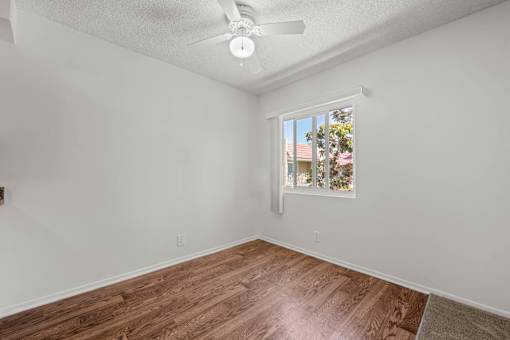 an empty living room with a window and wood floors